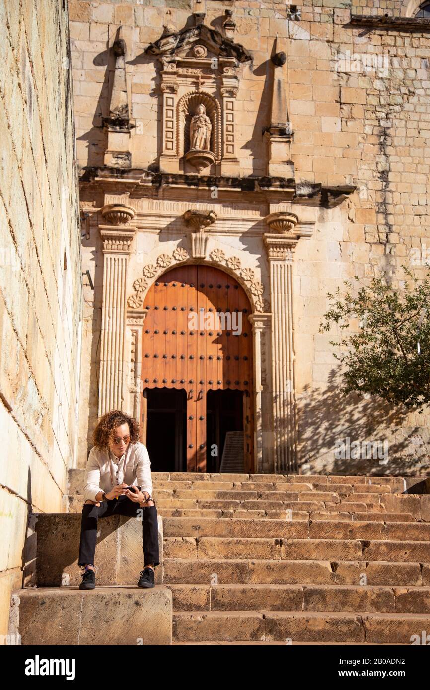 Mann mit iphone, auf der Treppe sitzend, außerhalb des barocken Tempels Stockfoto