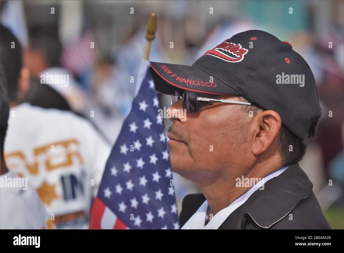 Ranghoher hispanischer Mann mit amerikanischer Flagge und einer Baseballkappe von San Francisco bei der Rallye Stockfoto