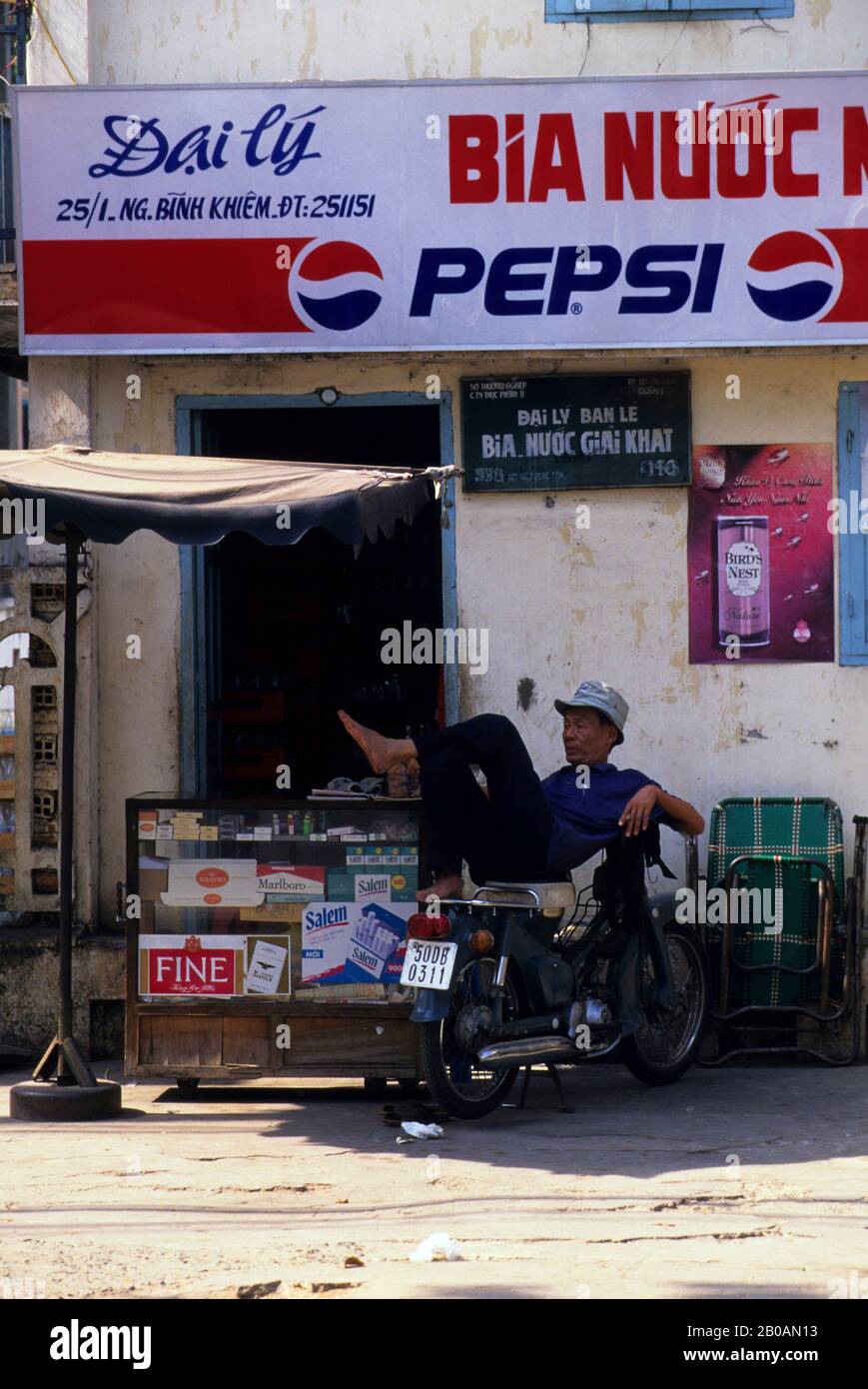 VIETNAM, HO CHI MINH CITY (SAIGON), STRASSENSZENE, PEPSI COLA SCHILDER, MAN LEGT AUF MOTORRAD Stockfoto
