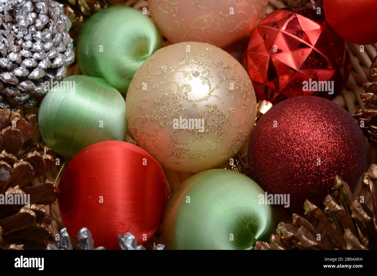 TIS THE SEASON: Weihnachtsschmuck und dekorative Tannenzapfen sitzen in einem Korb. Stockfoto