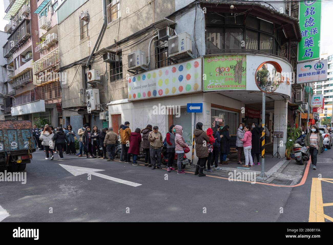 Taipei-Bewohner lassen sich in einer örtlichen Apotheke aufmachen, um rationierte Gesichtsmasken als Schutz gegen die Covid-19-Coronavirus-Epidemie zu kaufen. Stockfoto