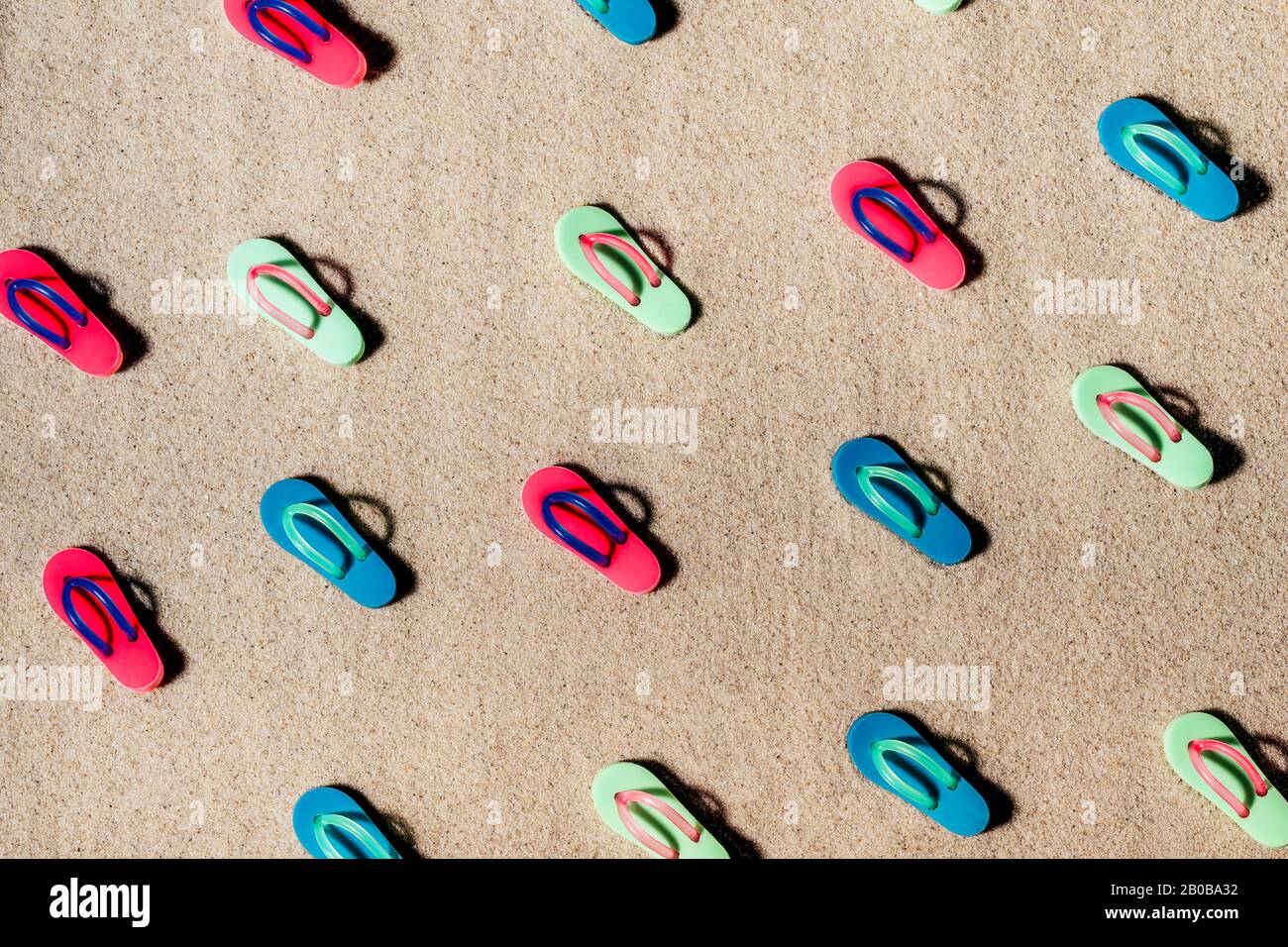 Muster von bunten Sandalen oder Dongs am Strand. Stockfoto