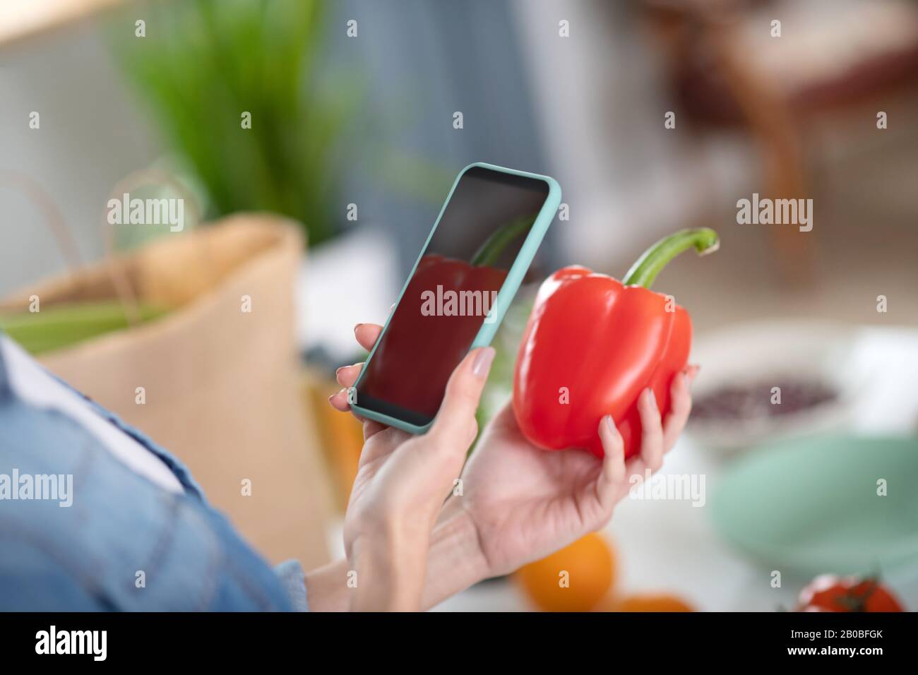 Weibliche Hände machen Fotos süßer roter Pfeffer auf dem Smartphone. Stockfoto