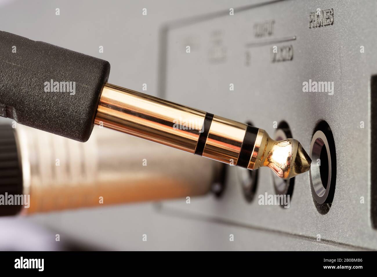 Nahaufnahme des Audio-Anschlusses der goldenen TRS-Telefonbuchse, der an die Buchse des Audiogeräts angeschlossen wird. Musik, Audio, Hi-Fi, Konnektivität und Tonwiedergabe. Stockfoto