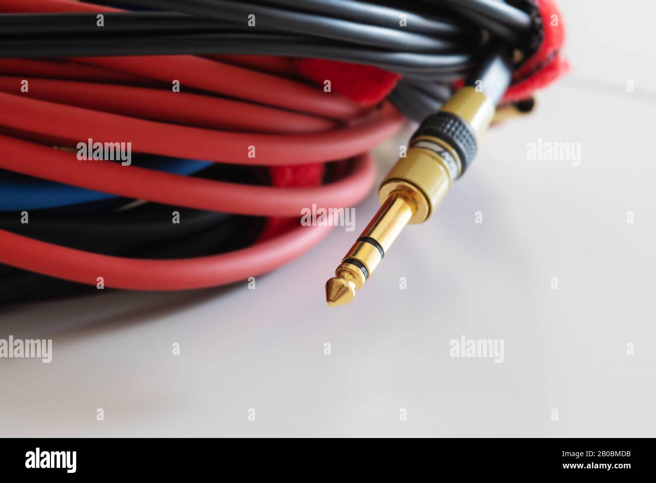 Gewickelte Audiokabel mit goldenem TRS-Telefonanschluss auf weißem Hintergrund. Musik, Audio, Hi-Fi, Konnektivität und Tonwiedergabe. Stockfoto