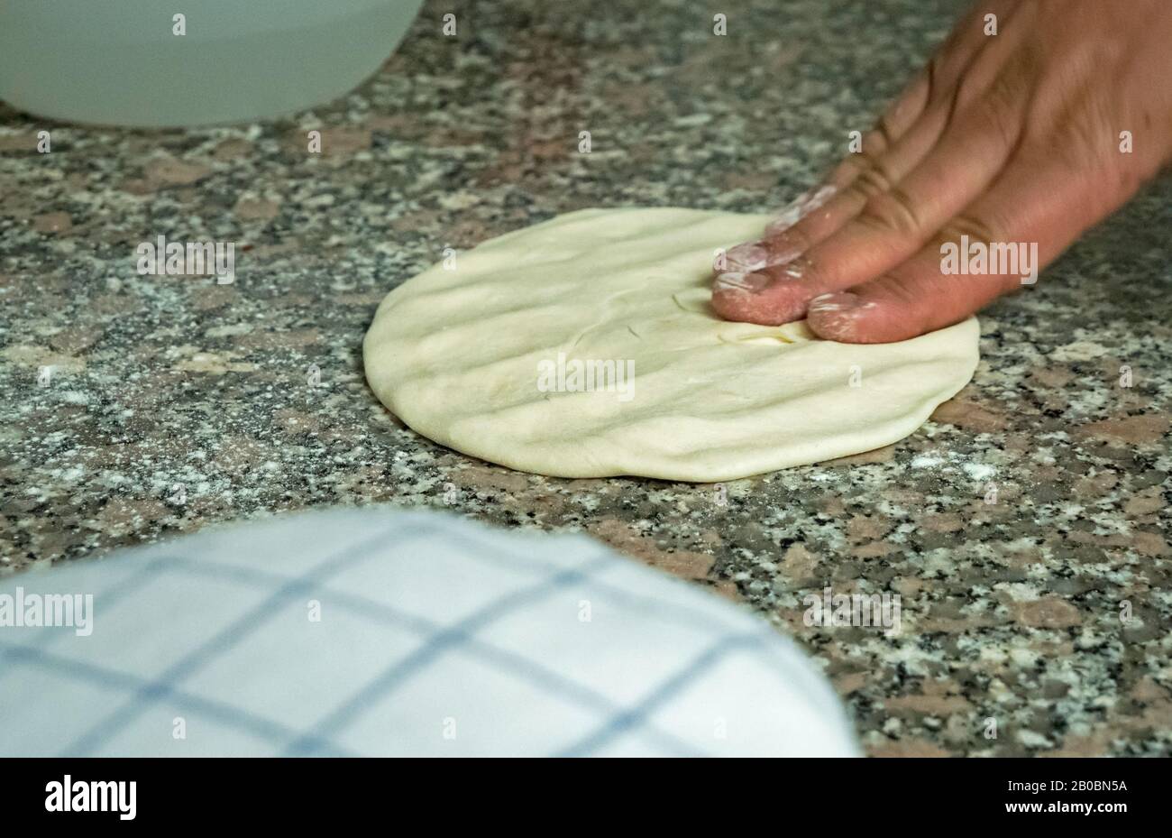 Ein Küchenchef würfelt und flacht naischen Brotteig auf einem Küchenarbeitdeck ab. Stockfoto