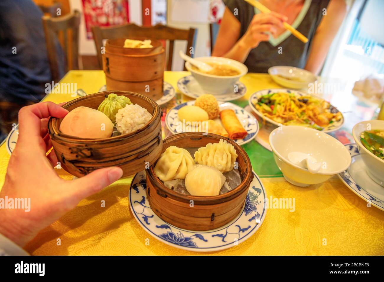 Tisch im chinesischen Restaurant in Yokohama Chinatown in Japan mit asiatischen Dampfklößen in einem Holzdampfer, gedämpften Brötchen, Ramen, Nudeln, Reis Stockfoto