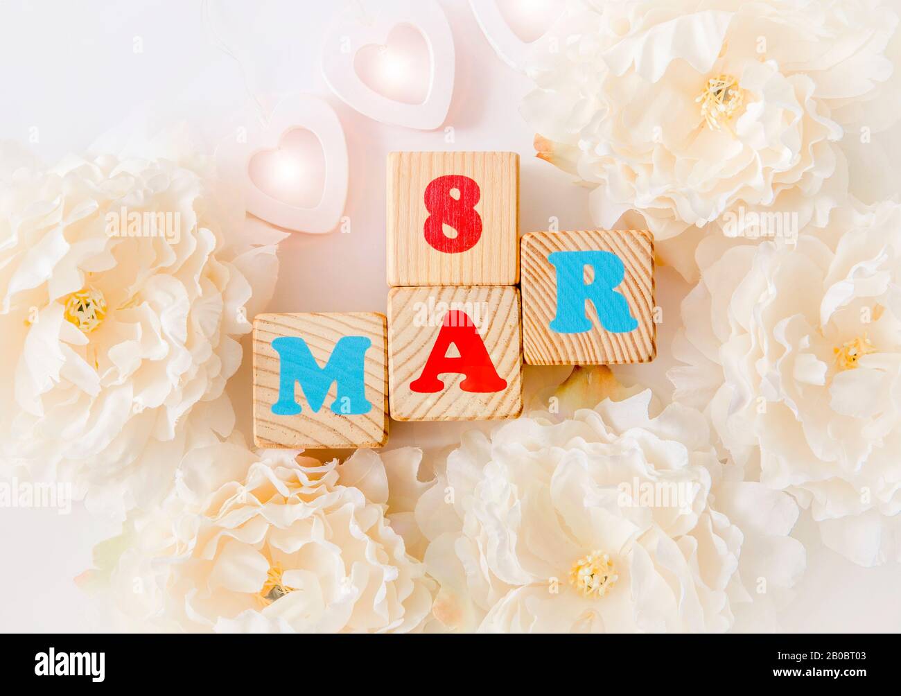 Internationaler Frauentag Kalender Grußkarte Hintergrund. Mit Holzherzen, pastellfarbenen Blumenblüten und Text 8. märz. Stockfoto