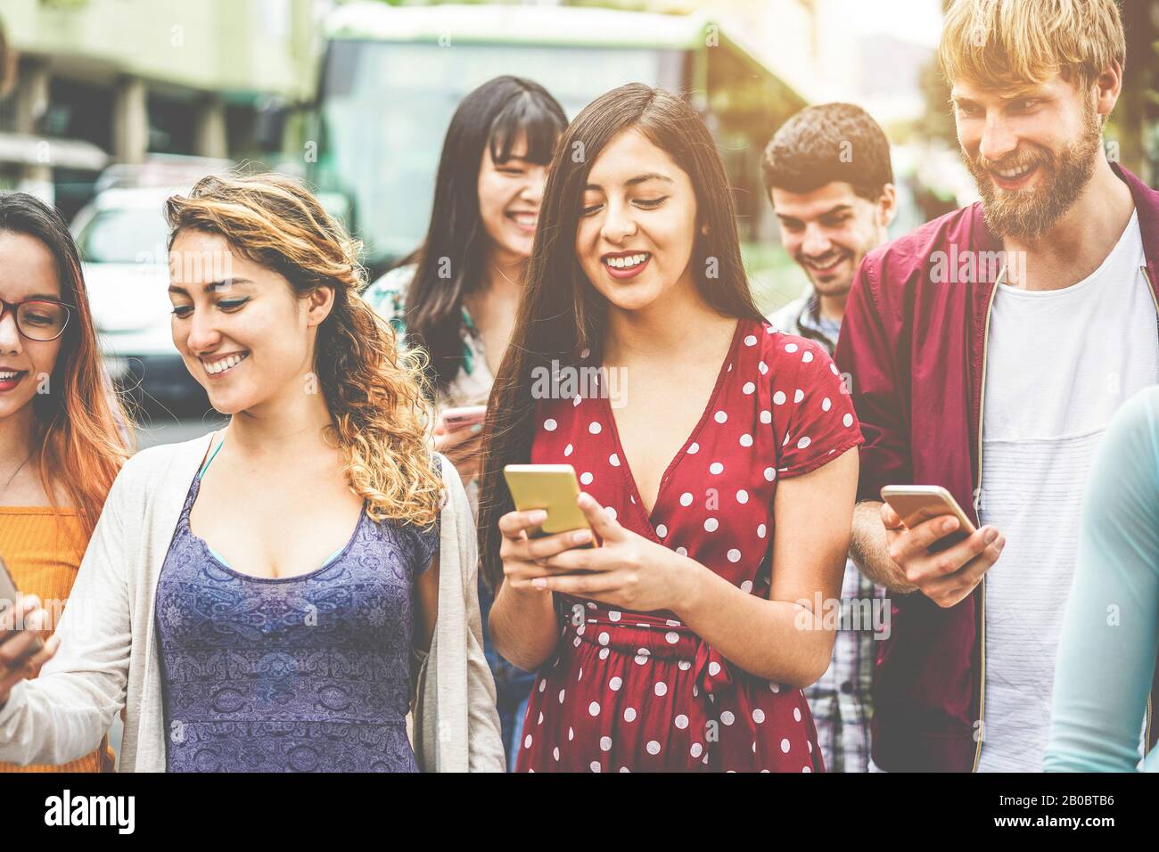 Fröhliche tausendjährige Freunde, die Smartphones am Busbahnhof nutzen - Junge Studenten, die nach der Schule im Freien Spaß haben - Freundschaft und Stadtlif Stockfoto
