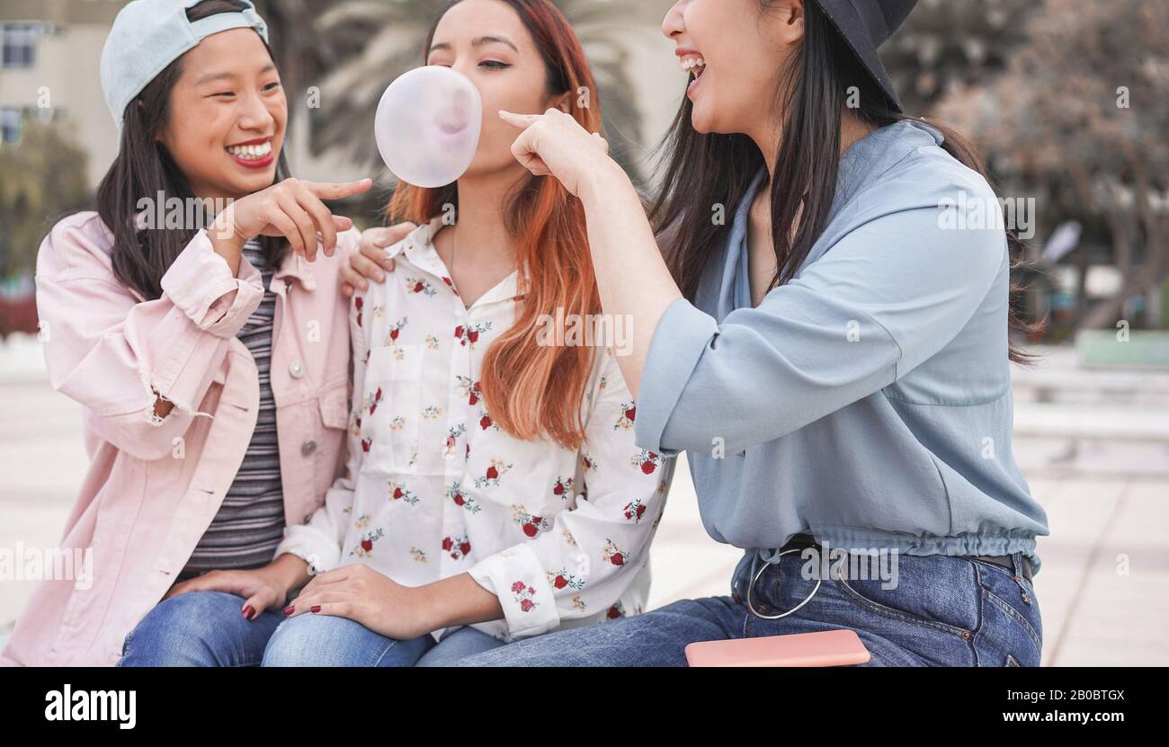 Trendige asiatische Mädchen, die im Freien zusammen Spaß haben - Junge Frauen, die mit Blasengummi spielen - Trends, Jugend, Jahrtausende Generation und Freundschaftskontra Stockfoto