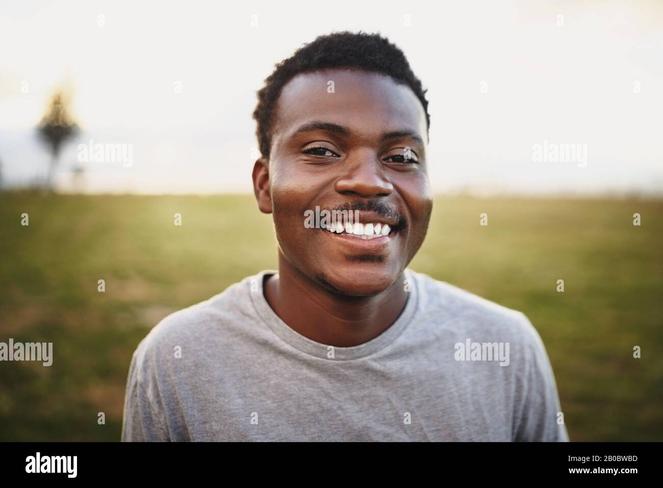 Porträt eines jungen afroamerikanischen Mannes lächelnd und mit Blick auf den Park Stockfoto