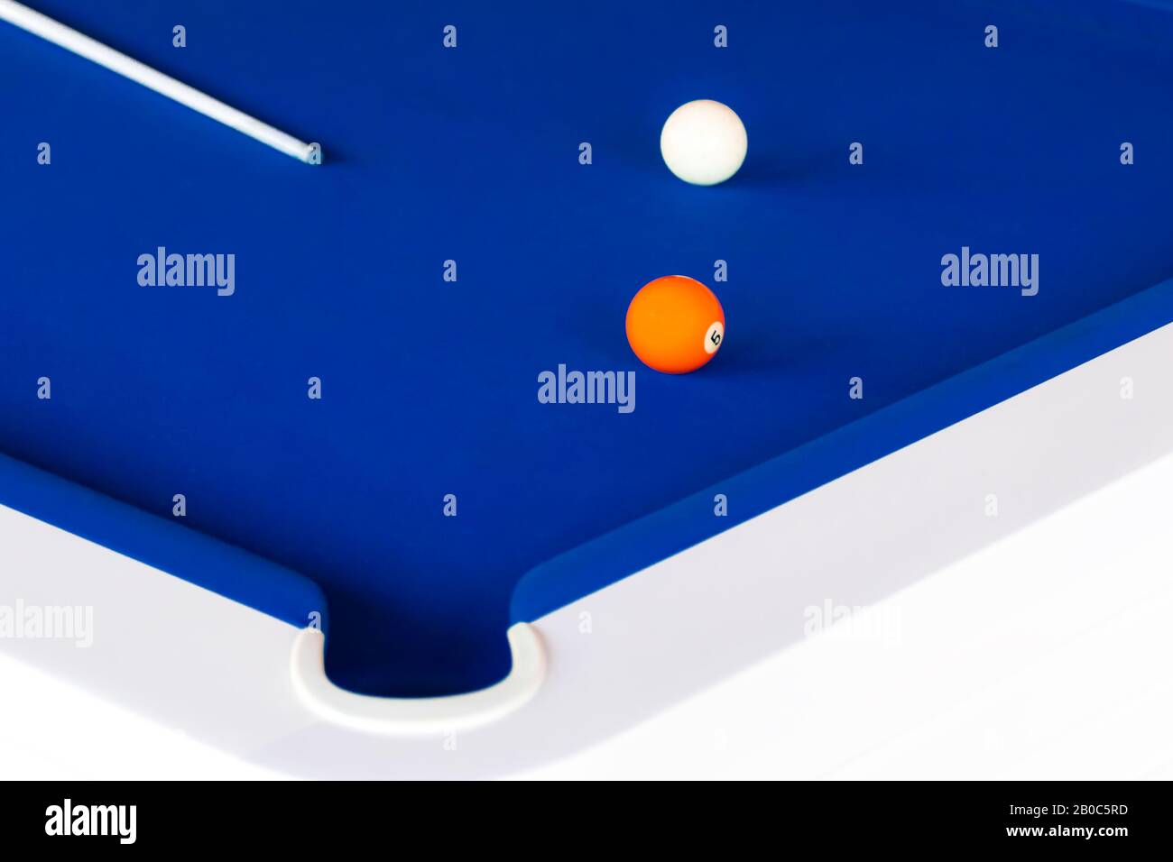 Ein blauer Billardtisch mit einem Cue, orangefarbenem Ball Nummer fünf und dem weißen Ball Stockfoto