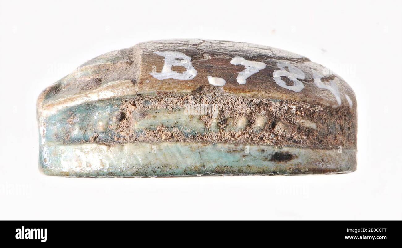 Scarab, Amonre, Die Dichtung ist in Form eines Skarabäus. Der Kopf mit Clypeus und der Körper sind durch eine gekerbte Linie getrennt. Eine zweite eingekerbte Linie folgt den Konturen des Kopfes. Es gibt keine Beine auf beiden Seiten, aber eine tiefe, von vertikalen Linien verzierte Rille läuft um das Objekt herum. In der ovalen Siegelebene wird der Name Amon-Re mit einem neb-schild unten und einer lotus-knospe mit einem linken hängenden Stamm buchstabiert. Das ganze wird von einem dekorativen Rahmen umrahmt, der aus zwei ovalen Rillen besteht, deren Linien senkrecht zu den Rillen ausgerichtet sind. Das Objekt ist längs perforiert, dicht, Skarabäus, grün Stockfoto
