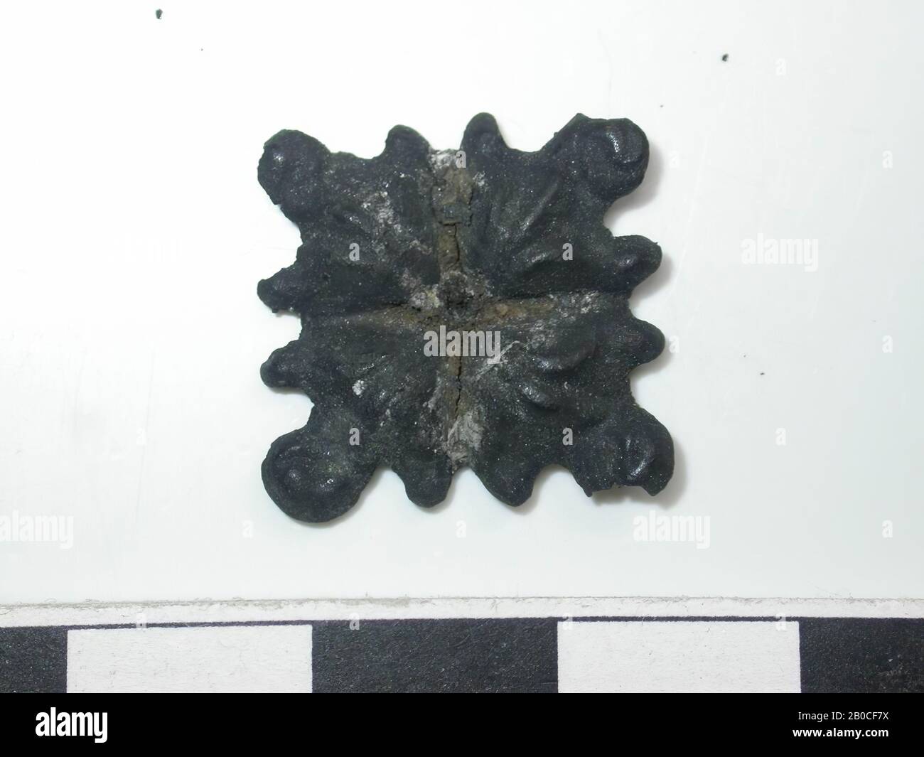 Quadratische Form, dunkel mit goldfarbenen Flecken (Kupferlegierung). Quadratische Form aus 4 Teilen. Auf jedem Teil gibt es drei Linien, die sich voneinander entfernen und in einer großen Perle mit zwei kleineren Perlen auf beiden Seiten enden. In der Mitte befindet sich ein Loch. Der Rücken ist hohl. Keine Bestätigung sichtbar., Bandhub, Metall, Kupferlegierung, H: 1,8 cm, W: 1,7 cm, D: 0,3 cm, Ende des 14. Jahrhunderts 1350-1400, Niederlande, Zeeland, Hulst, Verdronken Land Stockfoto