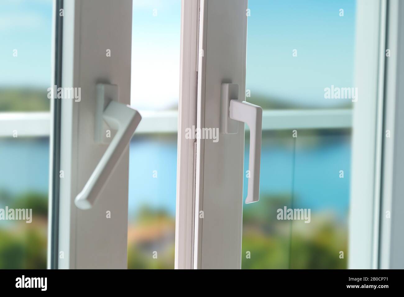 Schiebetür eines Balkons. Nahaufnahme des Schlosses an der Tür mit schöner Hintergrundlandschaft. Weiße PVC-Tür und Sicherheitsglas. Stockfoto