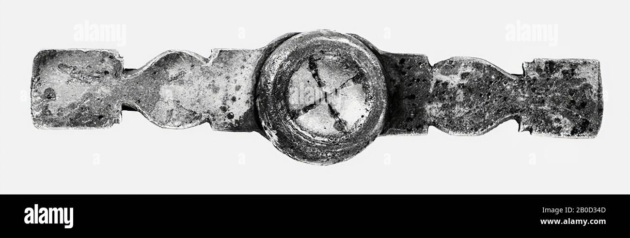 Band aus silveriertem Bronze. In der Mitte ist es mehr oder weniger oval und bis zu den Enden mit zwei Kerbpaaren auf beiden Seiten länglich, so dass das Band auf beiden Seiten des Mittelteils zunächst rechteckig, dann oval, dann rechteckig wird. In den extremen rechteckigen Teilen gibt es auch 1 Paar Kerben. Dekoration mit Stielen, die in Blättern enden. Im Stiftloch des Mittelteils wird mittels eines Stifts eine etwa Gleich große profilierte Scheibe befestigt. Ein bronzener Streifen (mit abgerundeten Enden) verläuft längs über den Rücken des Bandes und wird an beiden Enden von einer Stange und im gehalten Stockfoto