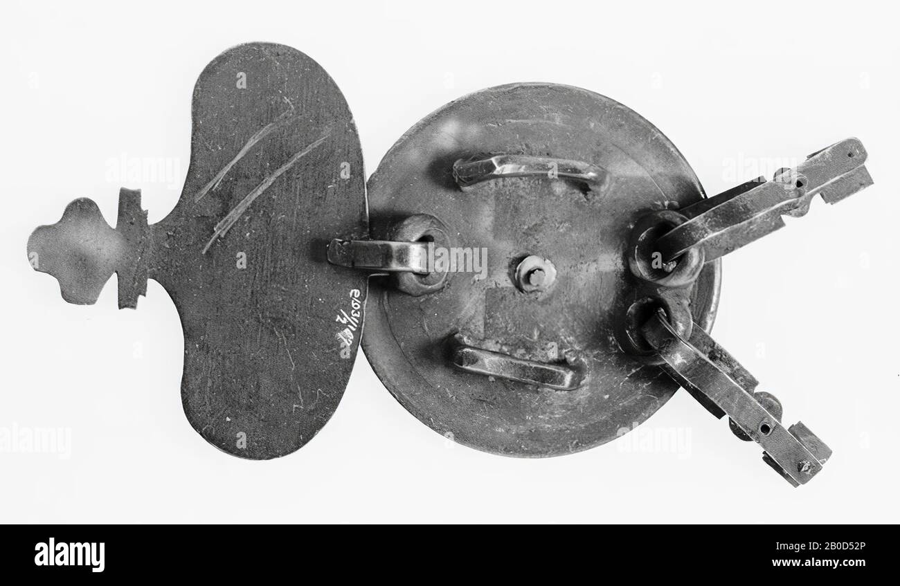 Große versilberte Bronze-Scheibe mit ovalem Anhängsel mittels 1 Ring zwischen der Mitte und der Unterkante. Zwischen dem mittleren und dem oberen Rand sind 2 Ringe gegeneinander angebracht, an denen längliche Anhängsel befestigt sind. Zwischen der mittleren und der Seitenkante befinden sich beidseitig 2 Tunnel. VZ-Antrieb: Flaches Mittelfeld durch einen Doppelbruch geschlossen. Darauf wurde eine Scheibe mit einem Stift befestigt (Dieser hat ein konkaves Mittelfeld mit einem Grat und einer konvexen Kante), dann ein konvexer Ring, der mit 4 Farnblättern verziert ist, die mit einem Doppelblütenmotiv abwechseln. Die einzelne Scheibe ist im Mittelfeld mit verziert Stockfoto