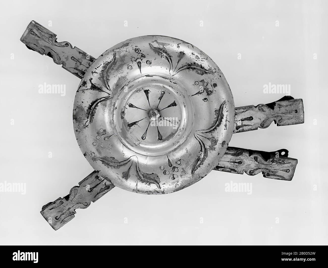 Eine große versilberte Bronze-Scheibe, an die jeweils 3 längliche Anhängsel mit Ring befestigt wurden. VZ. Scheibe: Ein konkaves Mittelfeld mit einem in der Mitte befindlichen Knoten, umgeben von einem Rand, zuerst konvex, dann konkave, von einem Grat abgeschlossen. Das Mittelfeld ist mit 8 aufrechten Blättern verziert, der Rand mit einer 4x Farnpflanze, die mit 4x einer stilisierten Blüte durchsetzt ist. KZ-Scheibe: Zwischen der Mitte und der Seitenkante befinden sich 2 Ringe gegenüber und 1 Ring zur Hälfte der anderen 2. Anhänge: Siehe E 1931 Stockfoto