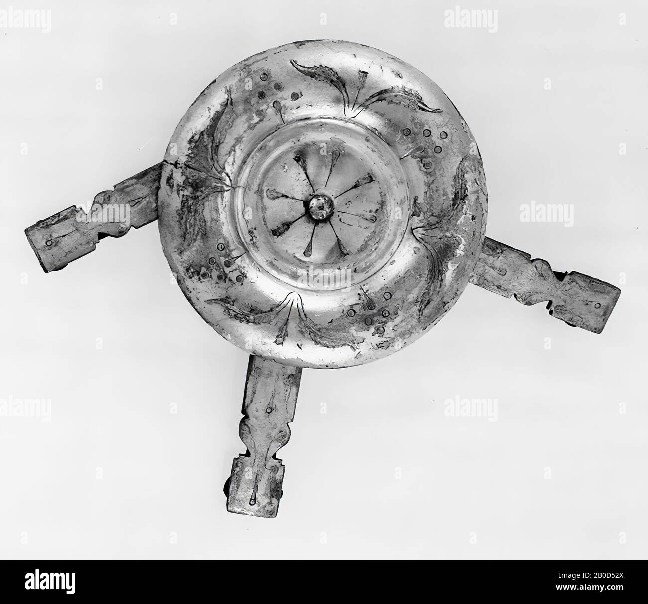 Eine große versilberte Bronze-Scheibe, an die jeweils 3 längliche Anhängsel mit Ring befestigt wurden. VZ. Scheibe: Ein konkaves Mittelfeld mit einem in der Mitte befindlichen Knoten, umgeben von einem Rand, zuerst konvex, dann konkave, von einem Grat abgeschlossen. Das Mittelfeld ist mit 8 aufrechten Blättern verziert, der Rand mit einer 4x Farnpflanze, die mit 4x einer stilisierten Blüte durchsetzt ist. KZ-Scheibe: Zwischen der Mitte und der Seitenkante befinden sich 2 Ringe gegenüber und 1 Ring zur Hälfte der anderen 2. Anhänge: Siehe E 1931 Stockfoto