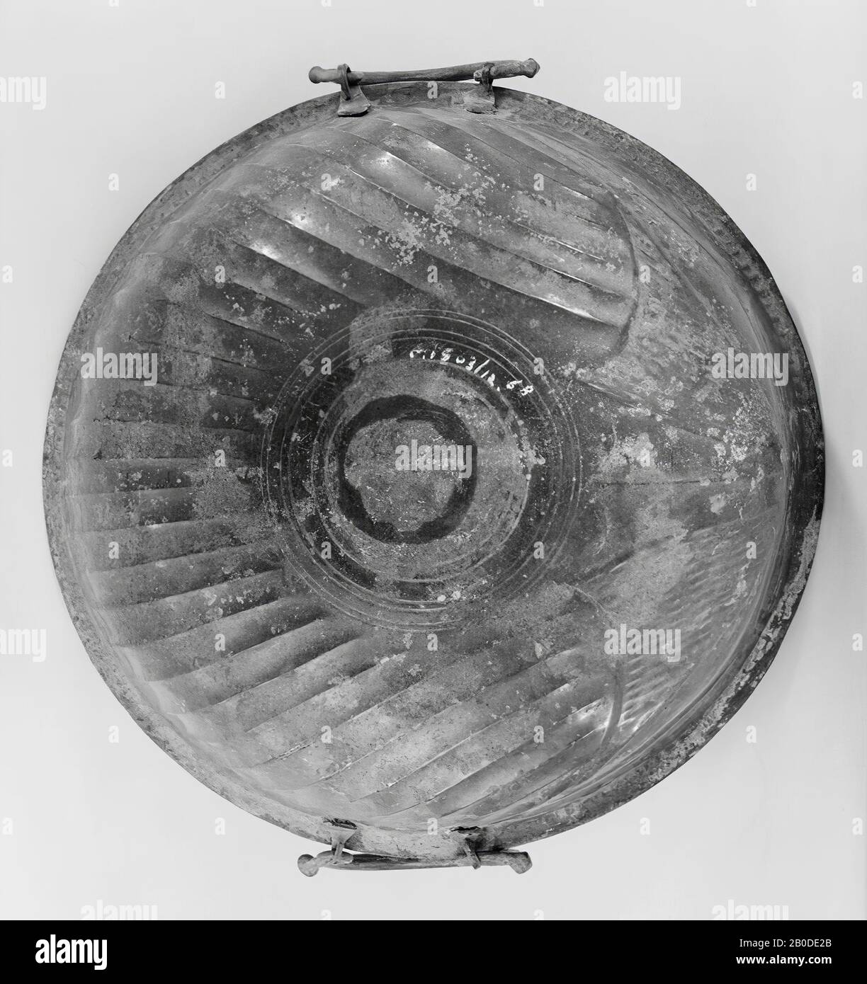 Steilwandiges Bronze-Becken mit gedrücktem Boden, außen mit acht, innen mit zwei Paar konzentrischen Rillen. Bei Flöten, deren Form sich von der Schalenform ableitet. Ein Paar omega-förmige Ohren, die an den blattförmigen Anhängen aus kleinen Blättern hängen. Entlang der schmalen, abstehenden Kante eine Dekoration aus vertikalen Rillen zwischen oben eine einzelne, unten drei Rillen. Sehr leicht beschädigt., Geschirr, Becken, Metall, Bronze, h. 9,2 cm, Durchm. 28 cm, roman 1-150, Niederlande, Gelderland, Geldermalsen, Geldermalsen, Bottesteyn Stockfoto