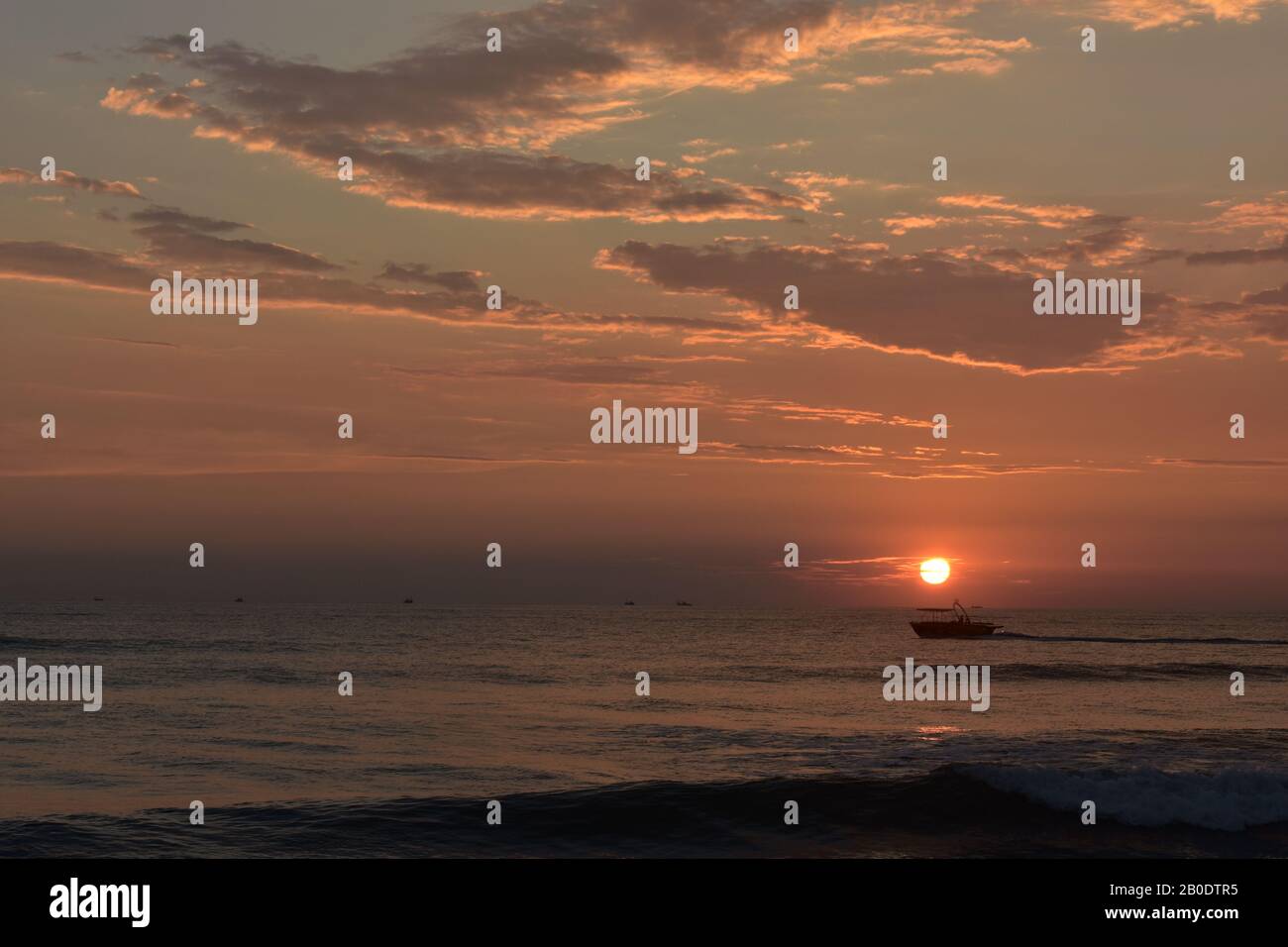 Ein Boot direkt unter der Sonne bei einem Sonnenuntergang in einem Ozean in goa Stockfoto