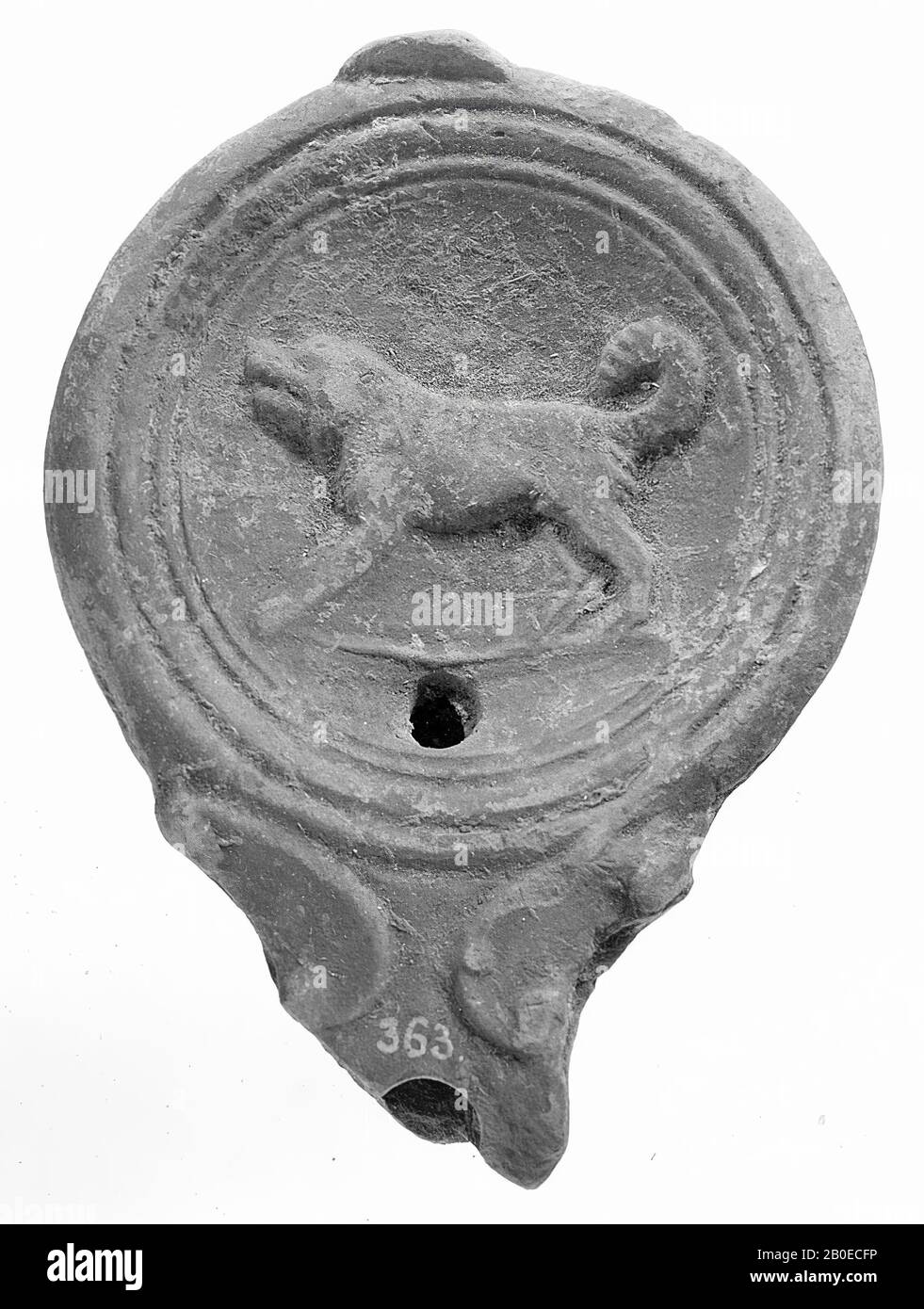 Eine rotlackierte Öllampe mit rundem Gehäuse. Der konkave Spiegel ist mit konzentrischen Kreisen umgeben und mit einem Reliefbild eines knurrenden Hundes verziert. Das kleine Füllloch befindet sich unter der Abbildung. Der breite, kurze Ausguss mit einem kleinen Feuerloch ist mit Voluten verziert. Marke: Halbkreis in Reliefarbeiten, Öllampe, Keramik, Terrakotta, 2,4 x 9,9 x 7,1 cm, 1. Und 2. Jahrhundert n. Chr. 1-200, Türkei Stockfoto