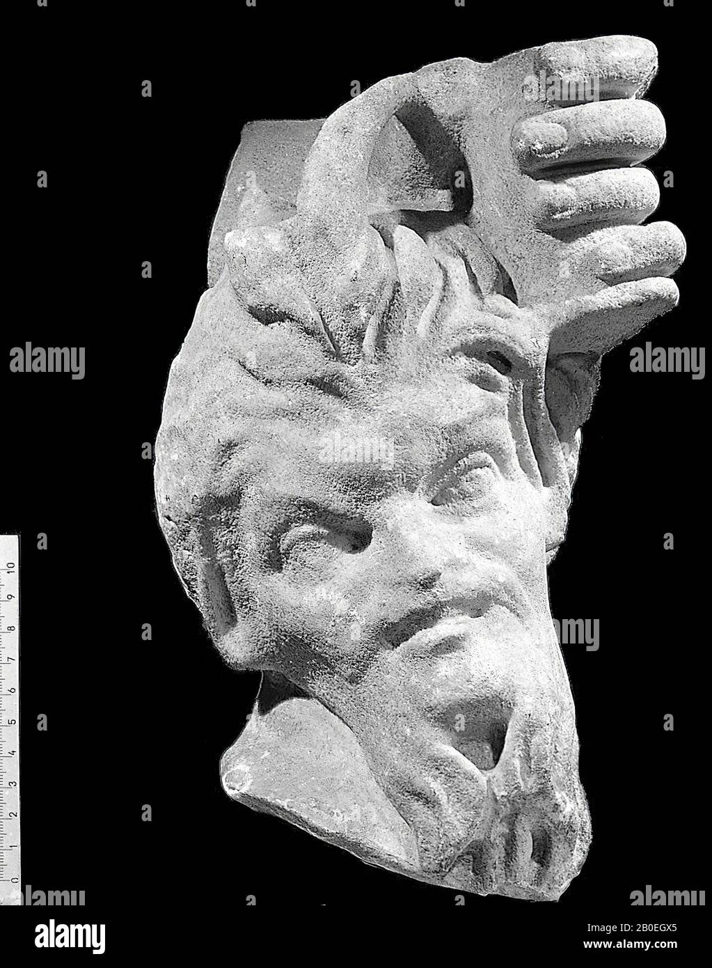 Kopf einer Papstfigur mit großen Hörnern und spitzen Ohren. Er hat einen Ziegenbart. Nach links hinter dem Kopf ragt ein Teil eines Pedums von hinten heraus. Oben auf dem Kopf befindet sich eine große linke Hand einer anderen Figur. Die Hand ist lebensgroß, der Panskop-Relat, Statue, Pan mit Hand der Venus oder Nymphe, Marmor, 29 cm, Kaiserzeit 0 Stockfoto