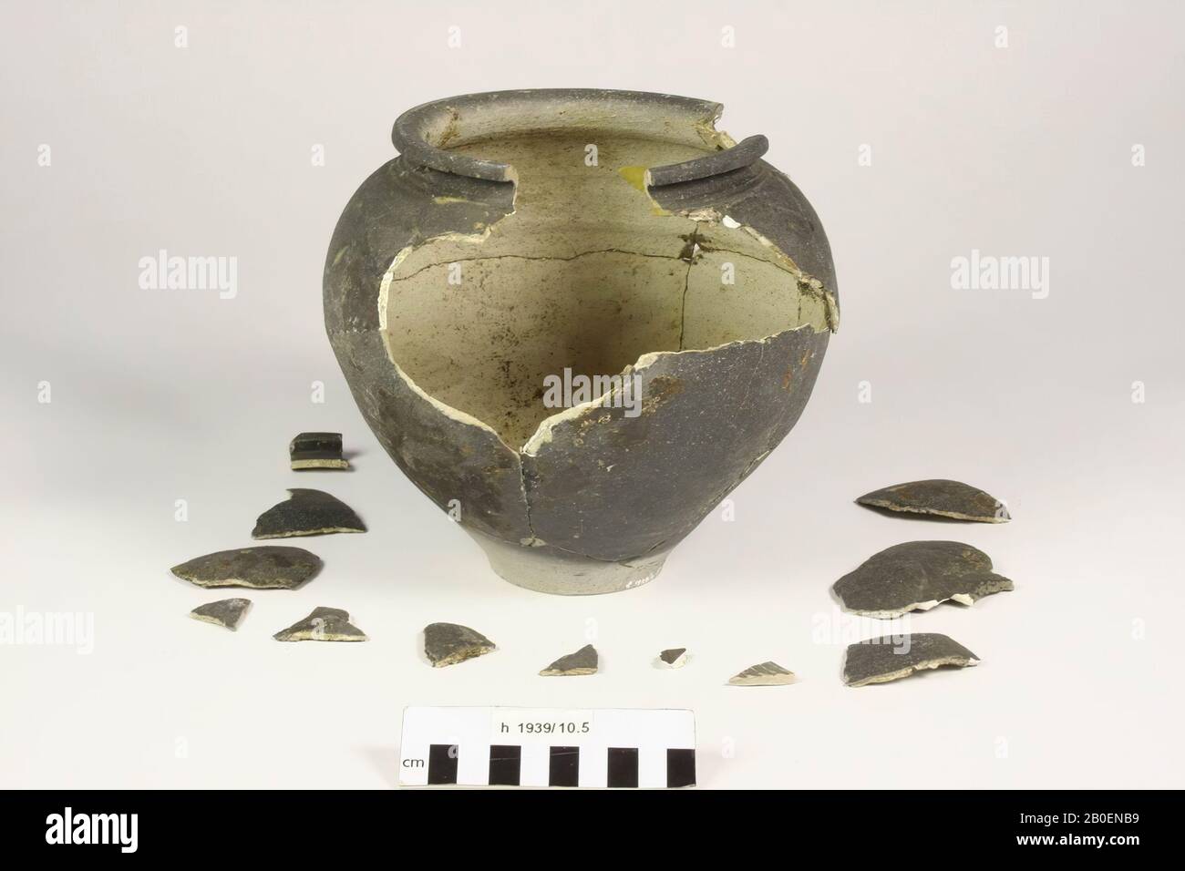Urne aus grauem, raubwandigem Steingut mit abgerundetem Rand. Altes Kleben, das mit Band zusammengehalten wird, 12 separate Bruchstücke, Spalt im Rand, großer Spalt im Rand Stockfoto