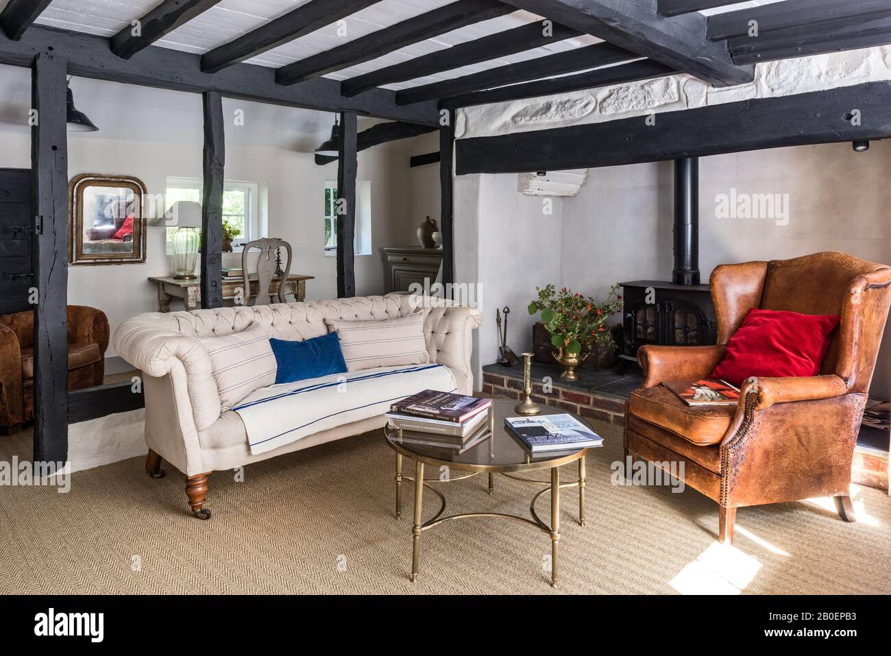 Fischgrätenfußboden mit viktorianischem Knopfsofa auf der Rückseite mit holländischem Ledersessel und dekorativem französischen Metall- und Glaskaffee aus der Mitte des Jahrhunderts Stockfoto