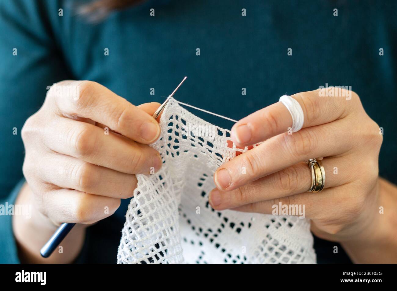 Handgearbeitetes traditionelles Strickwaren. Frau macht mit Nähnadel Leinwandmuster Nähte. Deckel mit Gewinde Stockfoto Handgearbeitetes traditionelles Strickwaren. Frau macht mit Nähnadel Leinwandmuster Nähte. Deckel mit Gewinde Stockfoto