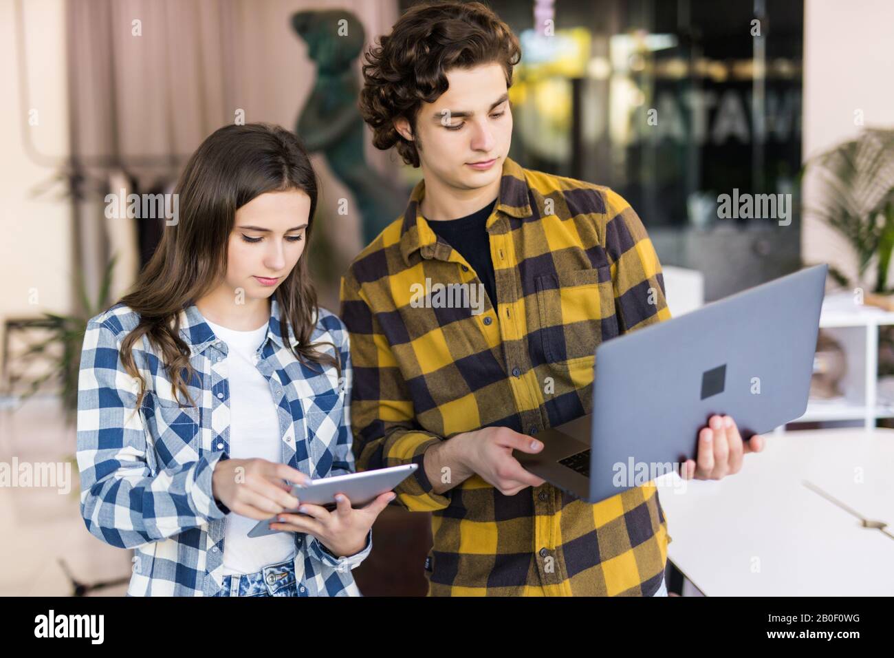 Aufnahme von zwei Designern, die in ihrem Büro arbeiten und dabei etwas auf ihrem Laptop zeigen. Stockfoto