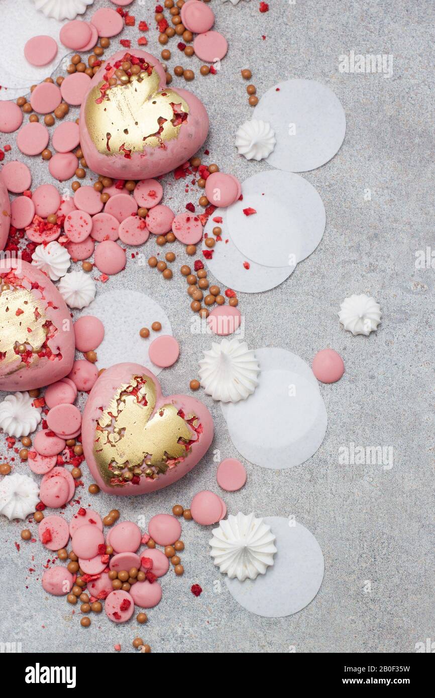 Rosafarbene Herzen aus gehärtetem Schokolade mit Schokoladentropfen, Meringues und getrockneten Beeren Stockfoto