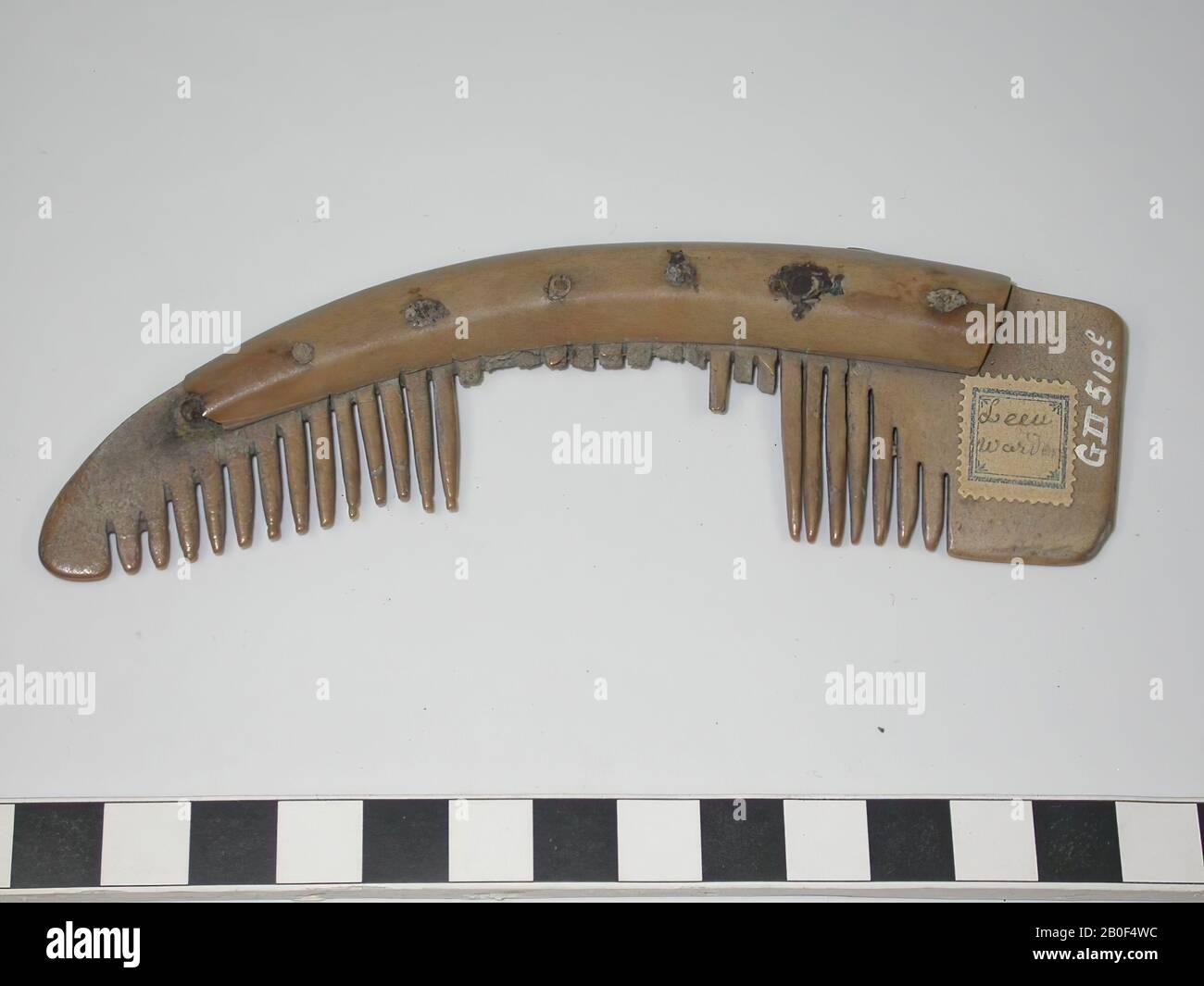 Einseitiger dreilagiges Kammaufsatz. Typ: Asymmetrischer Kamm mit einer rechteckigen Platte am Ende Dekoration: Undekoriert. Form: Gebogener Boden und gebogenes Oberteil. Zahnplatten: 5. Endplatten: 2. Gebrochene Zähne: 12. Ganze Zähne: 20, von denen eine Reihe von Licht abgenutzt ist und einige von ihnen ein kleines Stück der Unterseite haben. Ursprüngliche Anzahl der Zähne: 32. Nieten: 7. Platte auf den Kammaufsatz geklebt. Sägemarkierungen an den Griffblättern. So wurden zuerst die Zahnplatten und die Griffblätter aneinander befestigt und dann die Zähne eingesägt., Komb, organisch, Knochen, l = 13,6 cm und b = 3,8 cm., Vme 600-800, Niederlande Stockfoto