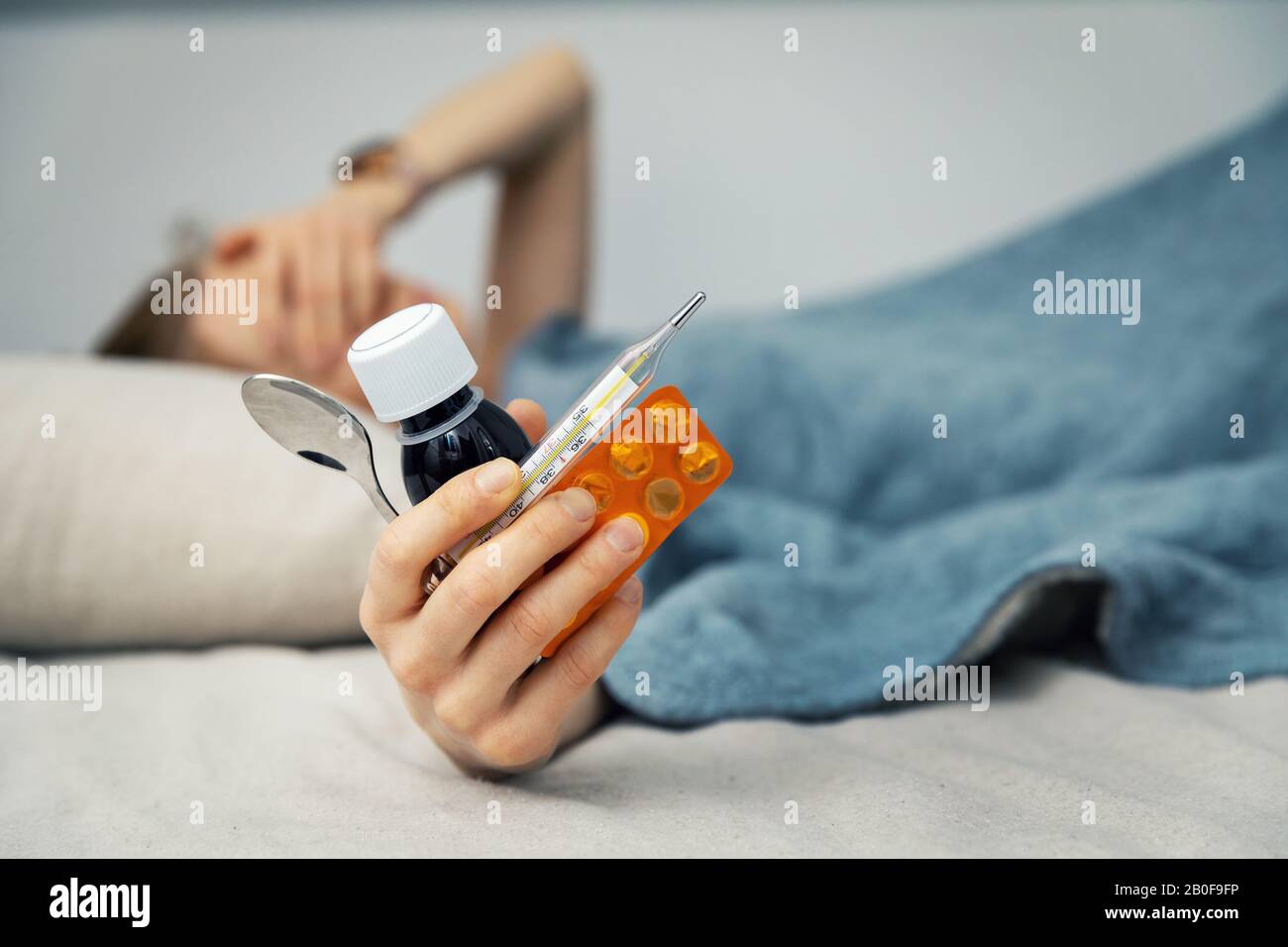 Kranke Frau, die zu Hause im Bett liegt und die Medizin in der Hand hält Stockfoto