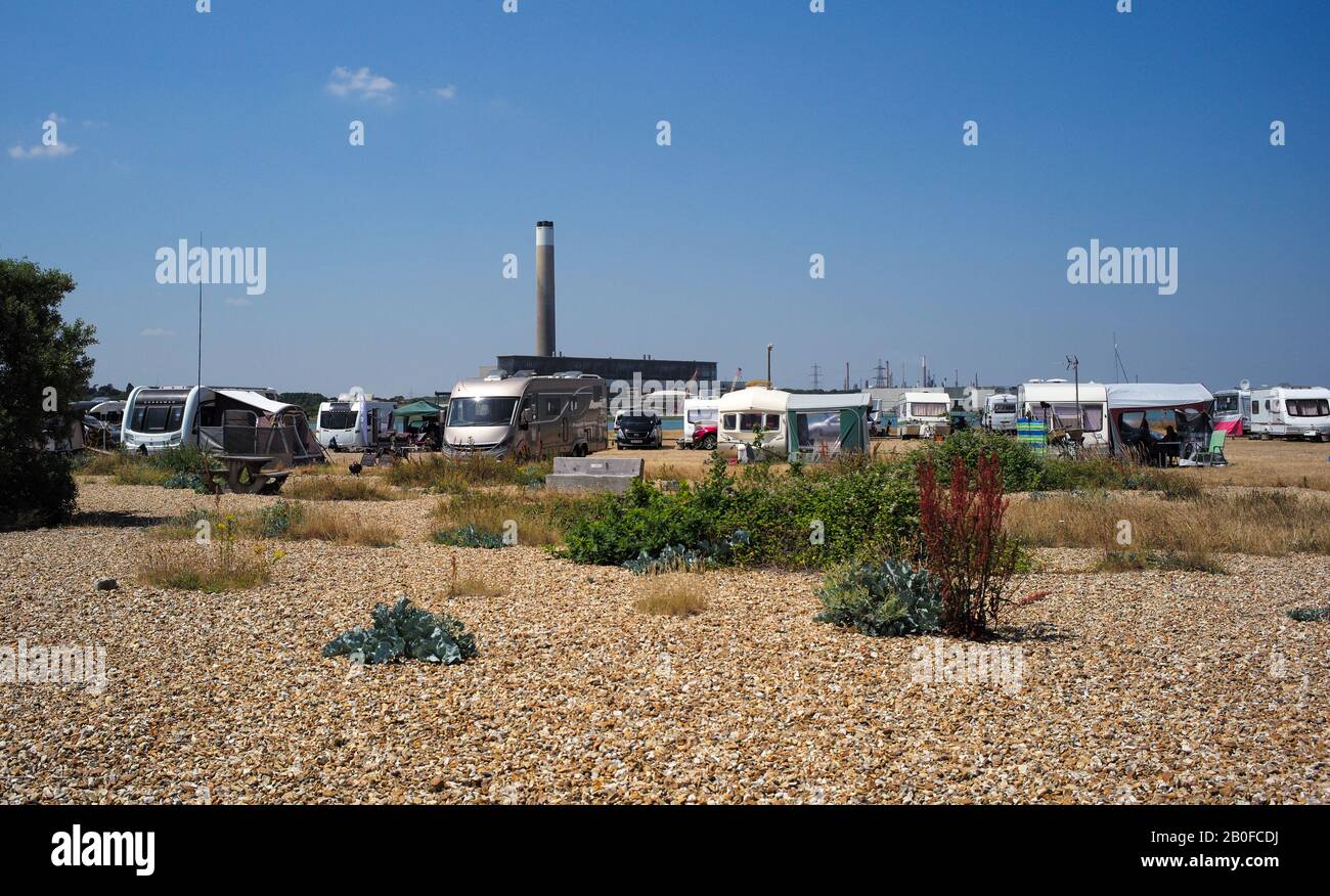 Ein Zimmer mit Blick, Wohnwagen und Reisemobile parkten am Strand am Fuße des alten Kamins des Kraftwerks Fawley, der abgerissen werden soll. Stockfoto