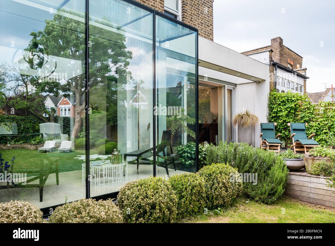 Eine Reihe von Büschen, die abgeschnitten waren, um die Linie zwischen Haus und Garten zu mildern Stockfoto