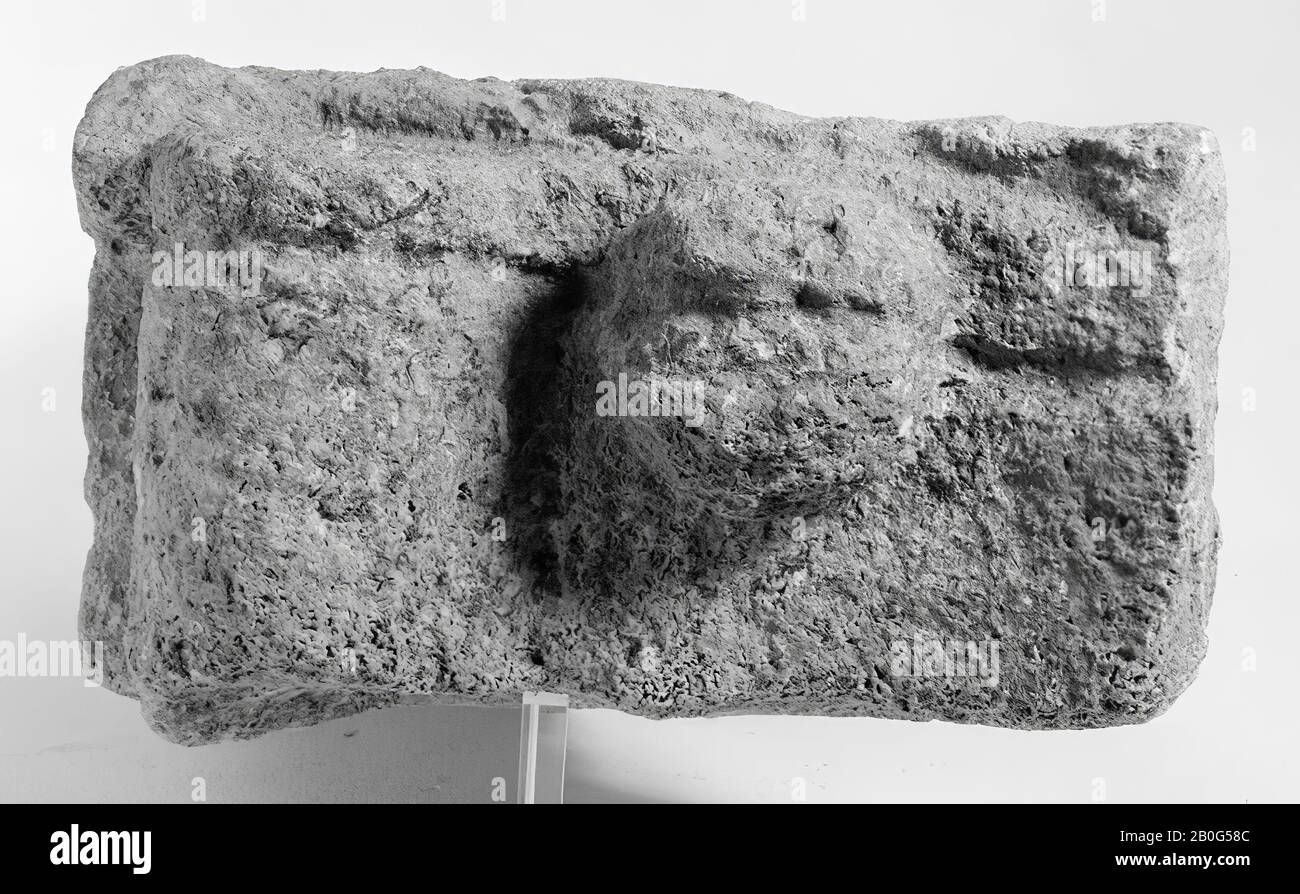 Rechter oberer Teil eines Altars ohne Aussparung. Kalksteine. Auf der Mensa, links von einer Rolle, befinden sich nacheinander zwei runde Früchte. Der Hauptrahmen ist vorne mit einer schmalen Zickzackkante verziert. Vorne und seitlich bildet sich ein schlichtes Gesims, das den Abschluss des Hauptrahmens bildet. Auf der rechten Seite befindet sich ein Cornucopiae mit drei (oder vier) kleinen runden Früchten an der Spitze, auf der Hälfte ist ein hängendes Blatt sichtbar. Der sehr verwitterte Rücken scheint nicht dekoriert gewesen zu sein. Aus den Resten der Umschrift lässt sich der Flügelaltar ableiten Stockfoto