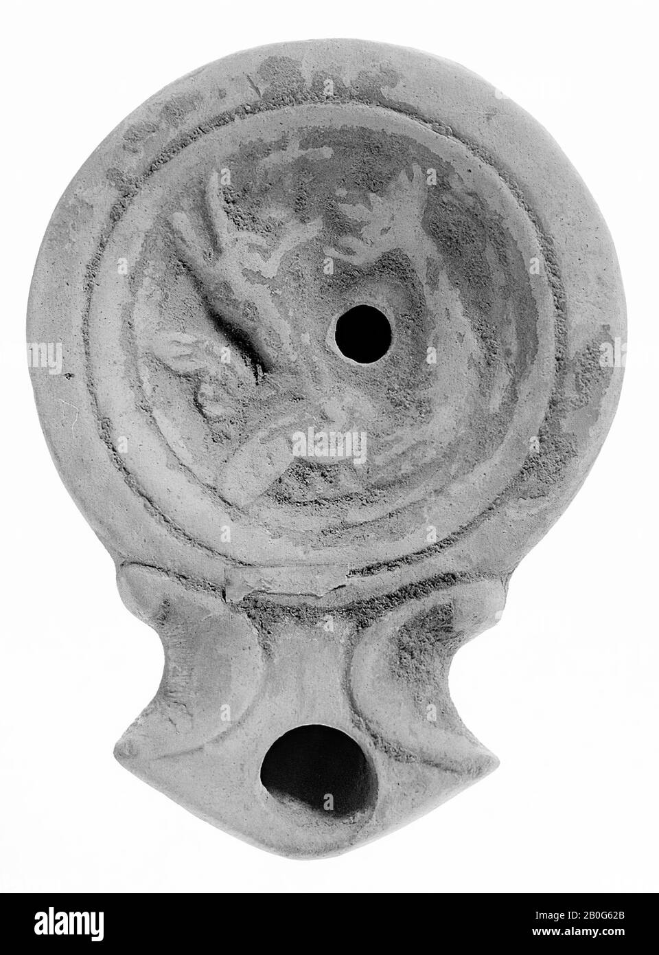 Eine Öllampe aus weißem Steingut mit runder Karosserie auf einem versenkten Sockel. Der konkave Spiegel ist von eingelassenen konzentrischen Kreisen umgeben und mit einer unklaren Reliefschau verziert (Seefiguren?). Das kleine Füllloch befindet sich in der Mitte der Figur. Der breite, kurze Auslauf mit großem Feuerloch ist scharf geschlossen und mit Voluten, Öllampe, Steingut, Terrakotta, 3 x 10,5 x 7,5 cm, 1. Und 2. Jahrhundert n. Chr. eingefasst. 1-200 n. Chr., Tunesien Stockfoto