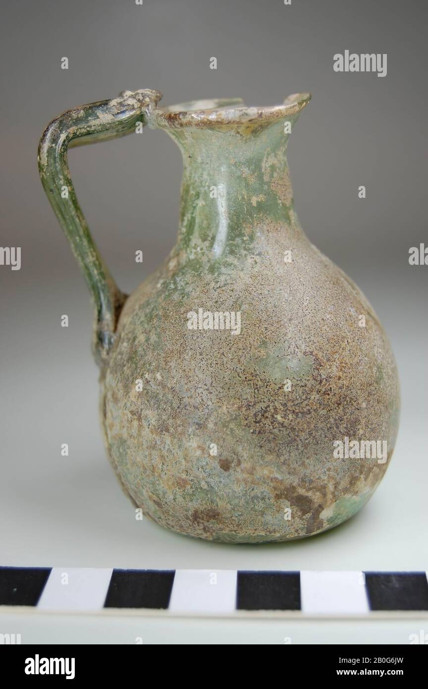Mixbecher mit einem Ohr. Der konvexe Bauch läuft nach oben. Kein Standring. Der Boden ist leicht nach oben. Marke Pontil. Dünnes, hellgrünes Glas, teilweise mit einer Verwitterungsschicht bedeckt. Einfache Kante. Das Ohr läuft diagonal zum Bauch, ist gerade gebogen und sitzt gegen die Lippe. Unter dem Ohrstarter befindet sich ein kleines Loch. Auf der Lippe fehlt ein kleiner Teil, Kanne, Glas, ca. 7,5 cm, Römerzeit, Türkei Stockfoto