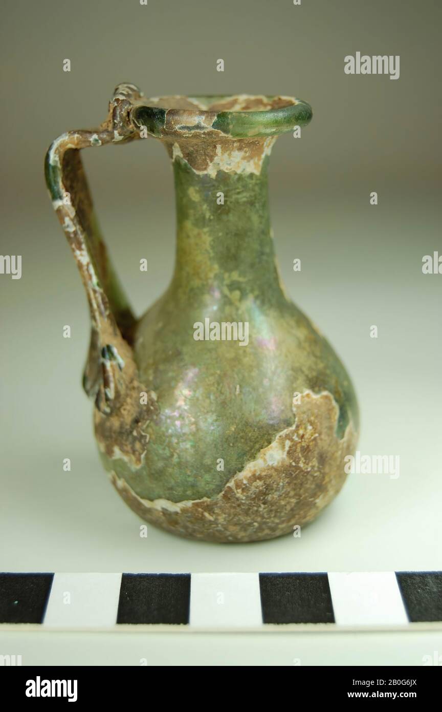 Mixbecher mit einem Ohr. Hellgrünes Glas, teilweise mit Verwitterungsschicht. Kein Standfuß. Der Boden steigt. Fast gerader Hals. Profilierte Lippe. Das Ohr läuft diagonal zum Bauch, ist gerade gekuppelt und sitzt gegen die Lippe, Kanne, Glas, 6,5 cm, römerzeit, Türkei Stockfoto