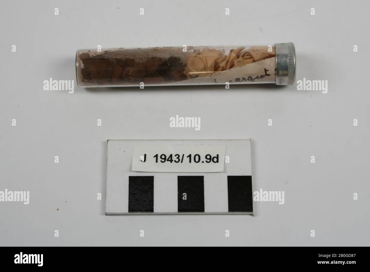 Reagenzglas mit Metallkappe, gefüllt mit Holzfragmenten, Leder, einem Papierwad und einer Notiz mit Text: Graf Center oberer Quadrant III, Skelett auf mattem Gehäuse mit roter Farbe, Reste von Leder, Umfang von Holz, schwarze Stücke in der Spitze des Grabes., Fragmente, Reagenzglas, Brief, organisch, Holz, Leder, Glas, Metall, Papier, Reagenzglas: 8,8 x 1,7 cm, Vorgeschichte, Ukraine Stockfoto