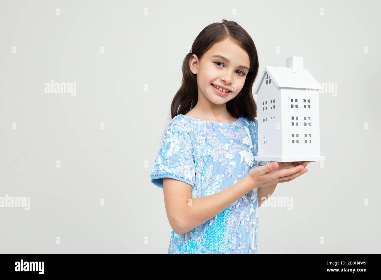 Teenager-Mädchen mit einem Modell des Hauses in den Händen auf weißem Hintergrund mit Kopierraum. Unbewegliches Eigentum Stockfoto
