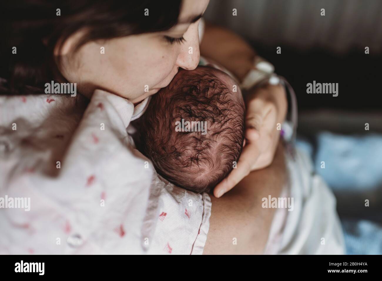 Mittelansicht der Mutter im Krankenhausbett küssen Kopf des neugeborenen Sohnes Stockfoto