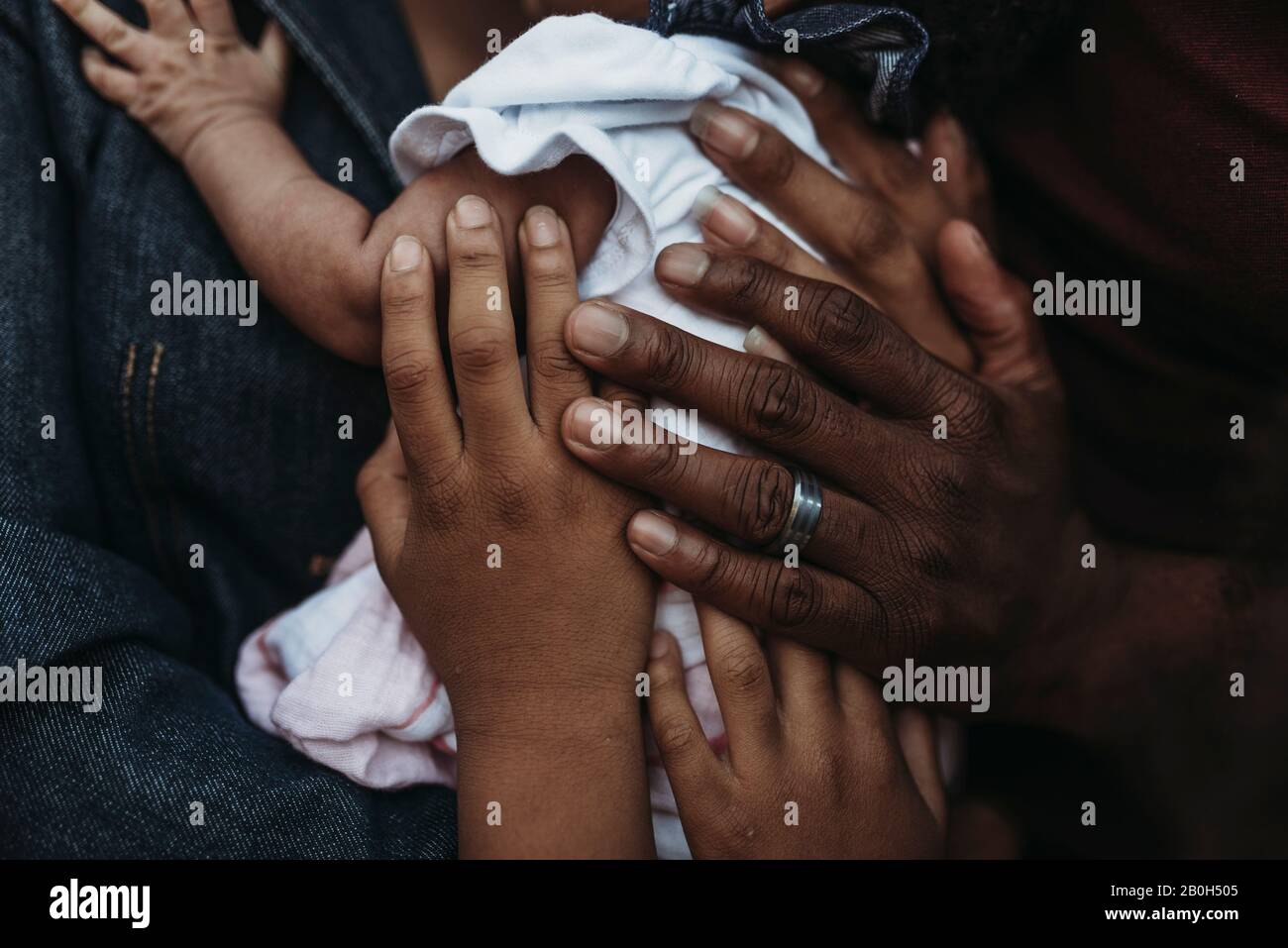 Nahaufnahme der Hände der Familie, die alle das Neugeborene halten Stockfoto