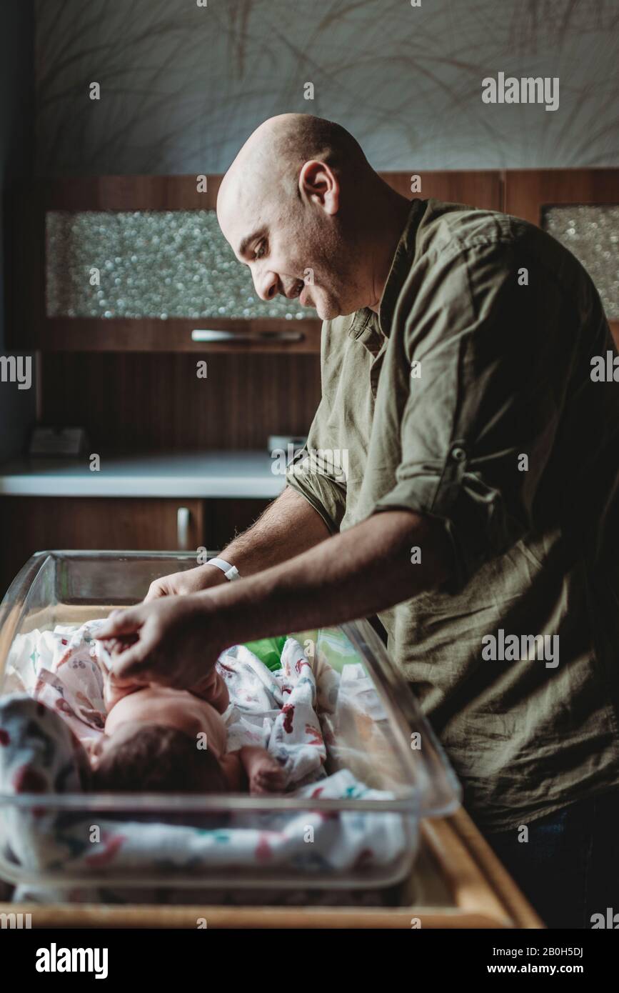 Papa ändert neugeborenen Sohn Windel im Krankenhaus durch Fenster Stockfoto
