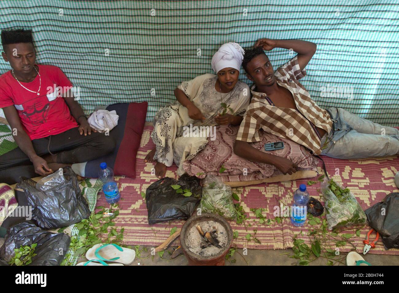 02.11.2019, Adama, Oromiyaa, Äthiopien - EINE Frau und zwei Männer sitzen auf dem Boden und kauen Khat. 8000 Binnenvertriebene aus der Region Somalia leben in vier refu Stockfoto