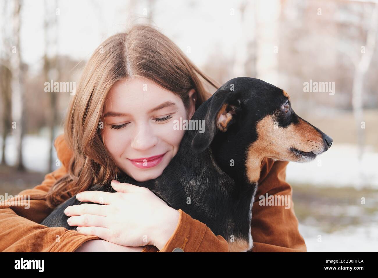 Der Mensch ist glücklich mit einem Hund. Konzept für liebevolle Haustiere: Glückliche junge Frau umarmt ihren Dachshund bei einem Spaziergang Stockfoto