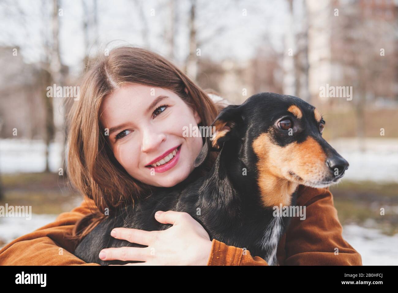 Der Mensch ist glücklich mit einem Hund. Konzept für liebevolle Haustiere: Glückliche junge Frau umarmt ihren Dachshund bei einem Spaziergang Stockfoto