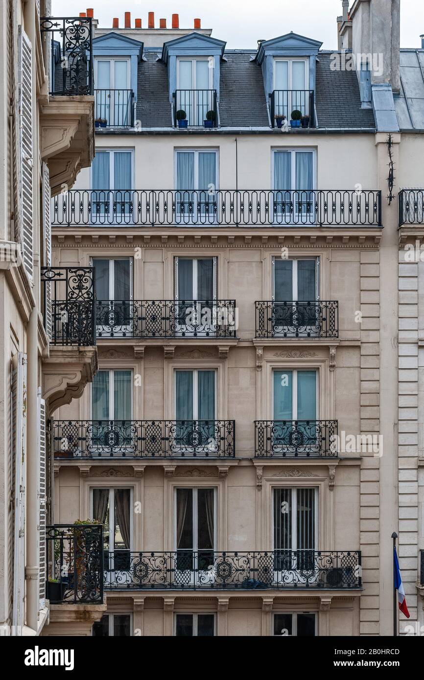 Pariser Haus mit Fenster, Balkons und Dachgauben gegen eine beige Wand. Aus den Fenstern der Weltserie. Stockfoto