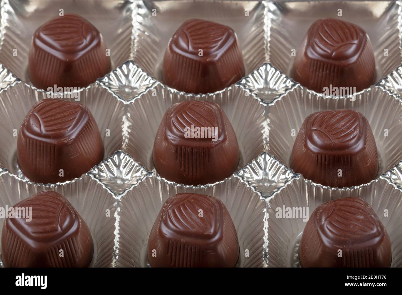 Sortiment an Luxus-Schokoladenbonbons in weißer Schachtel isoliert auf weißem Hintergrund. Schokoladen-Set mit exklusiven handgefertigten Süßigkeiten. Kopierbereich Stockfoto